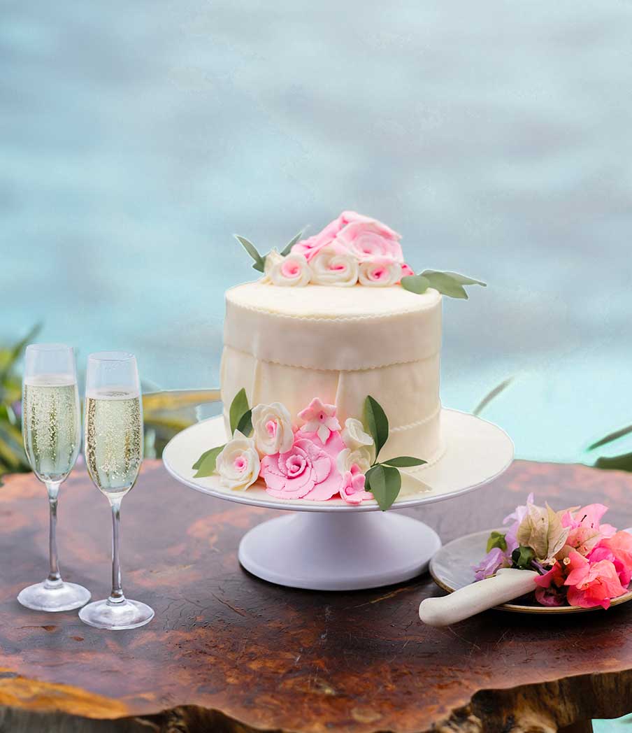 wedding-cake-pink-flowers-knife-2-champagne-glasses-wood-table-close-up-lagoon-