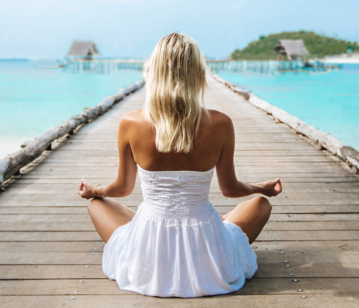 journey-to-wellbeing-girl-meditating-jetty-white-dress-700x600px