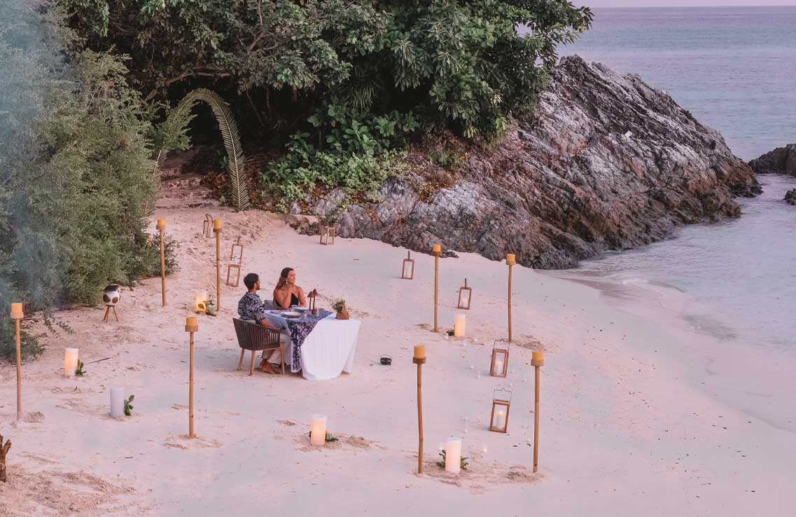 romantic-couple-beach-dinner-candles-lagoon-pink-hour